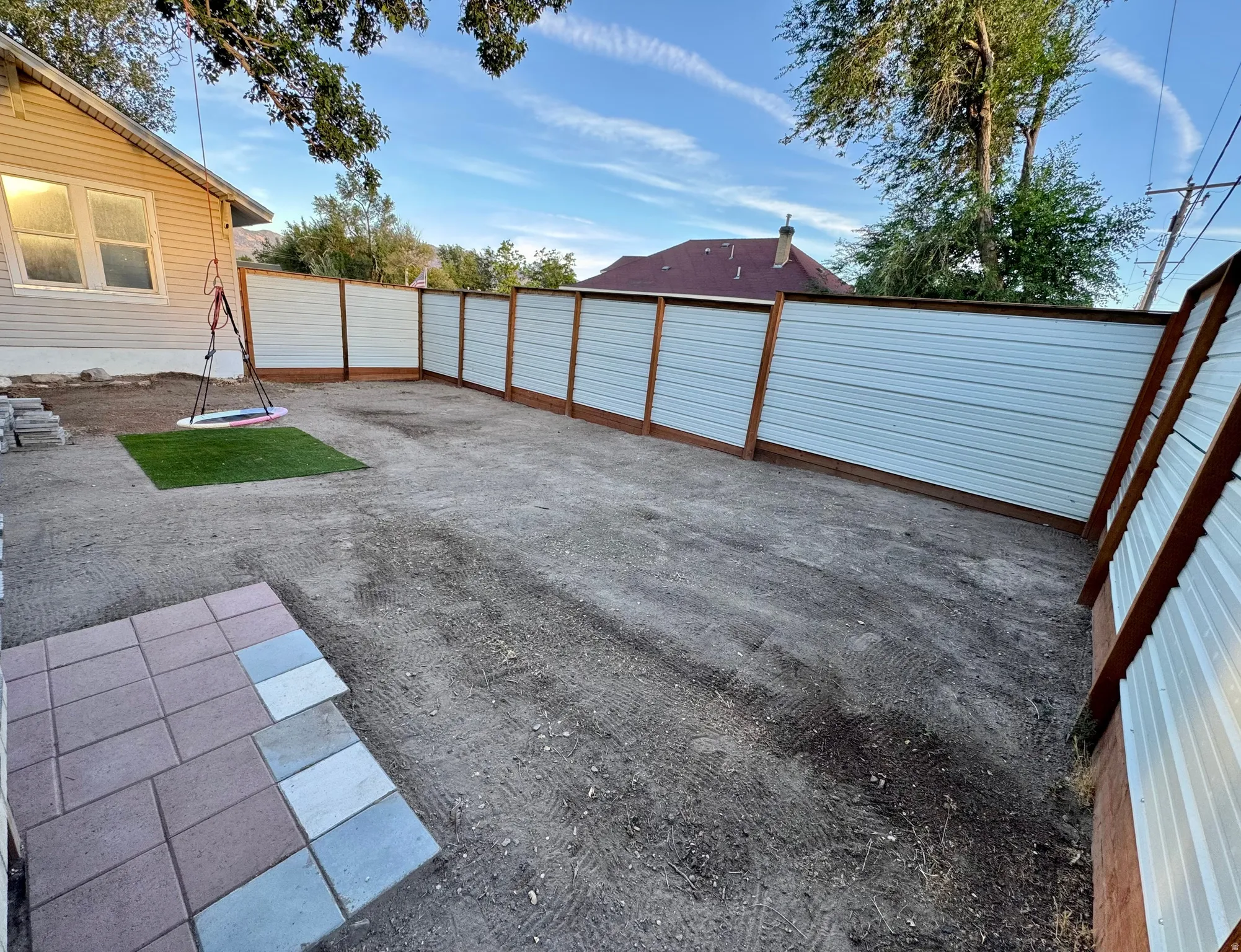 Spacious rear yard with new privacy fencing, partially installed paver patio, and an artificial turf section