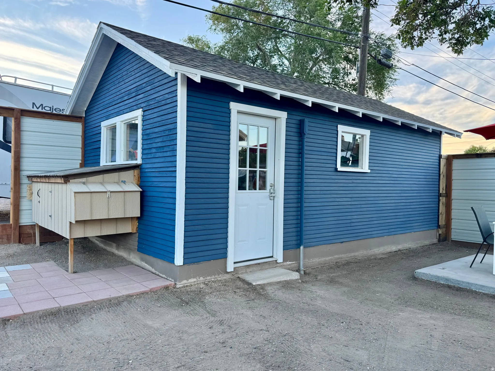 Charming blue garage workshop featuring horizontal siding, white trim accents, and a pitched roof