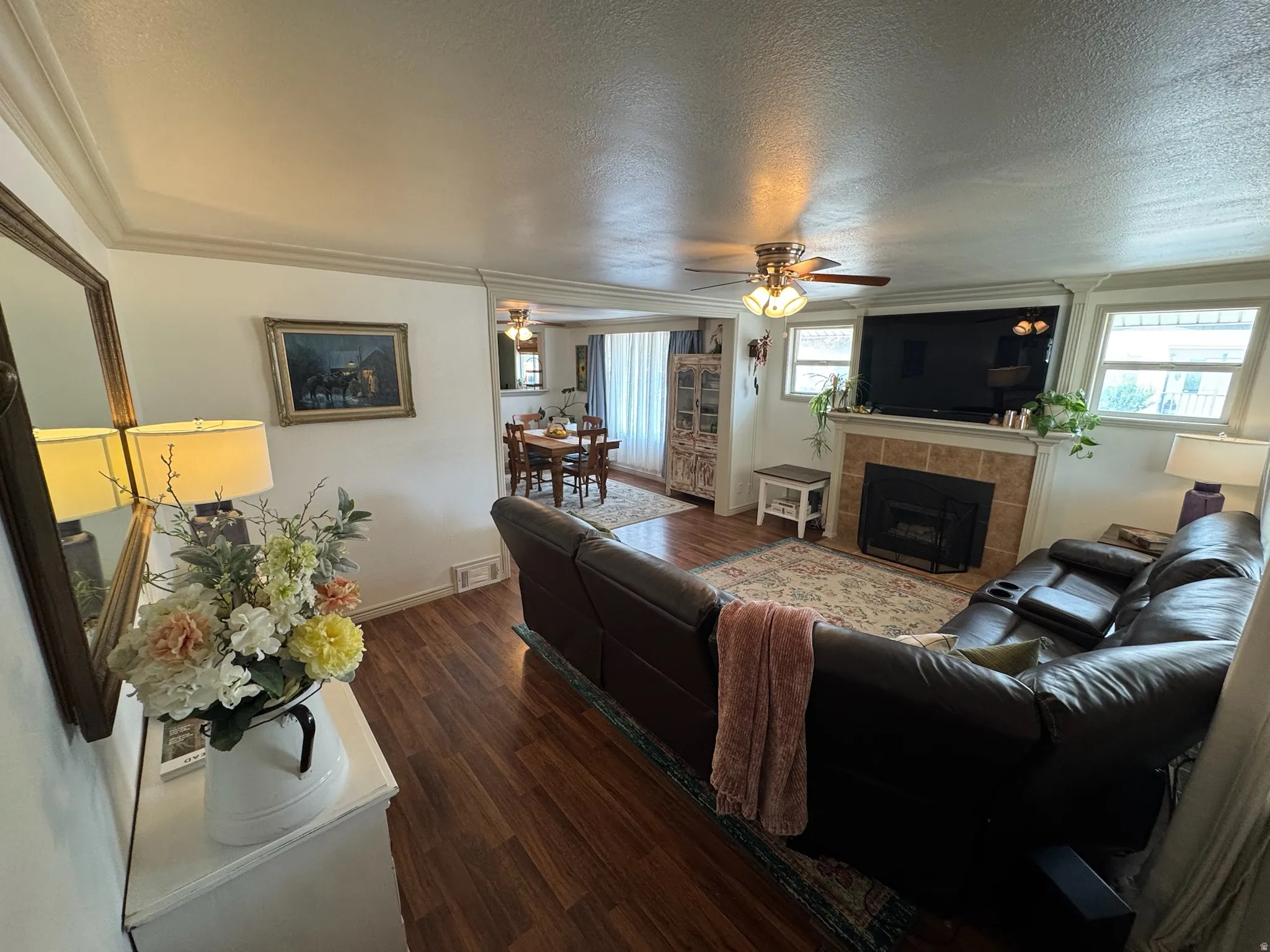 Wood-finish flooring throughout, crown molding, and a tiled fireplace