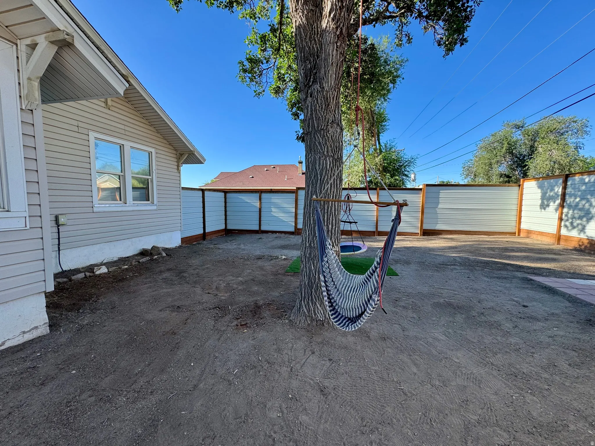 Spacious backyard with a mature tree, privacy fencing, and a side-gabled exterior