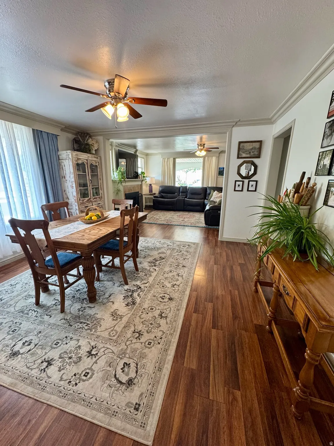 Wood-finish flooring throughout, crown molding, and ceiling fan with light fixture