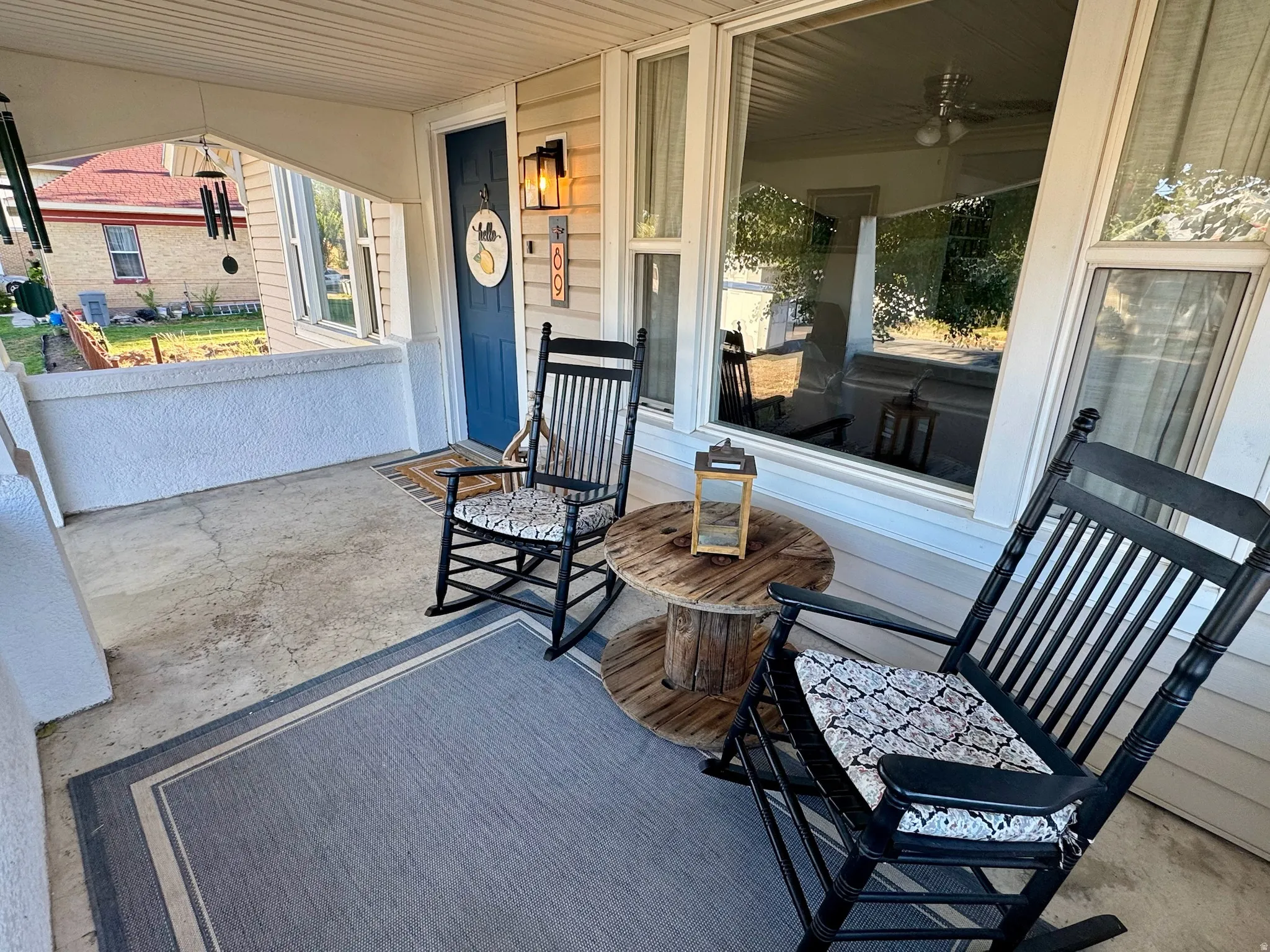 Covered front porch with concrete flooring and a blue entry door