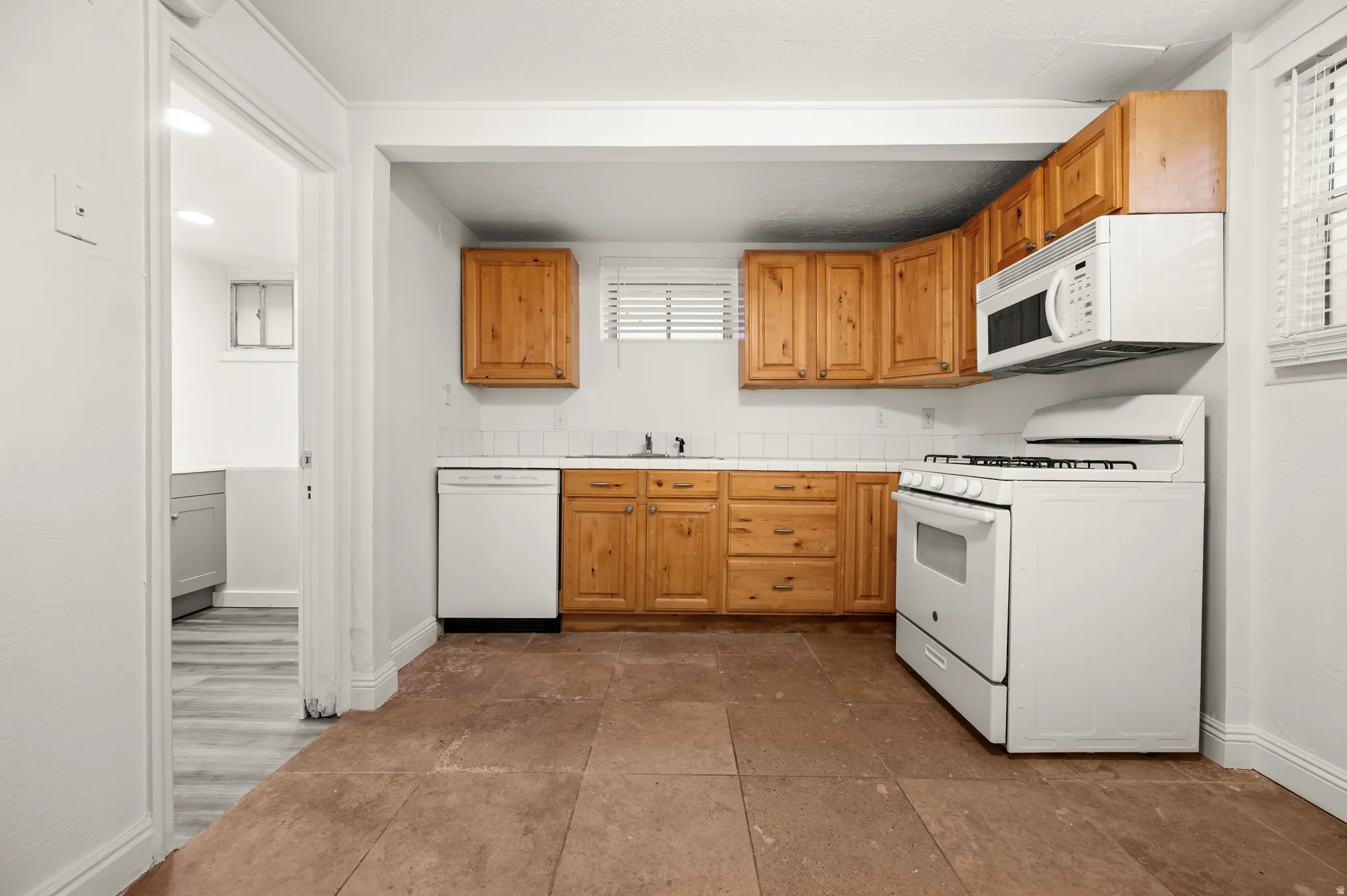 Kitchen featuring wood cabinetry, white tile backsplash, and tile flooring