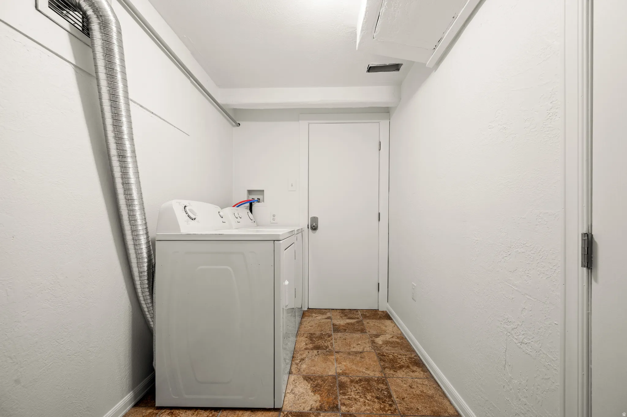 Laundry area featuring tiled flooring, a built-in dryer vent, and a white interior door