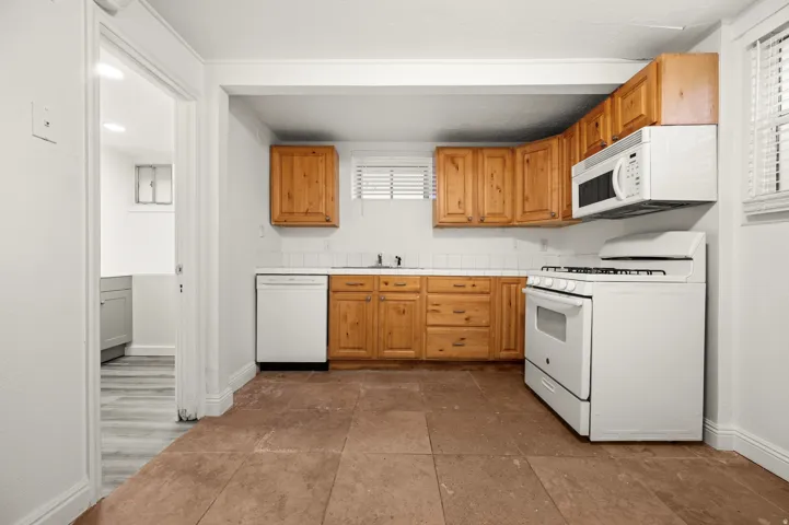 Kitchen featuring wood cabinetry, white tile backsplash, and tile flooring