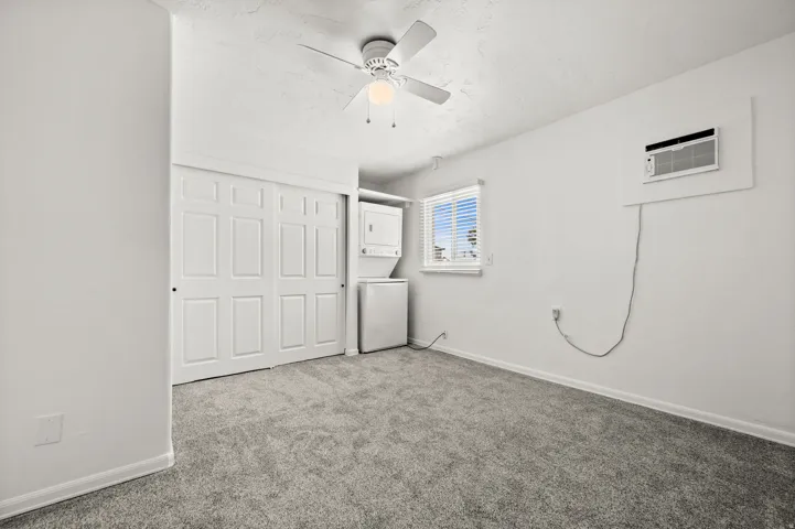 Wall-mounted air conditioning unit, ceiling fan with integrated lighting, built-in window with blinds, and white sliding closet doors