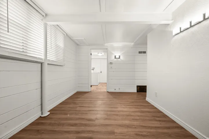 Wood-finish flooring, white shiplap wall accents, multiple window openings with blinds, and recessed lighting fixtures