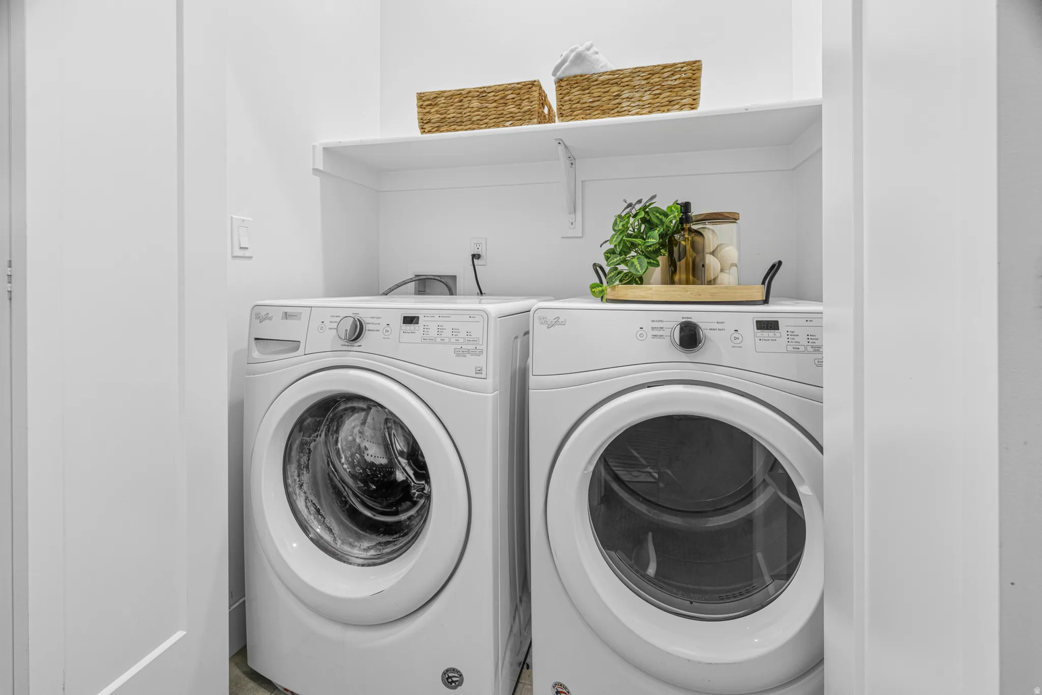 Laundry area featuring front-loading machines and an overhead storage shelf