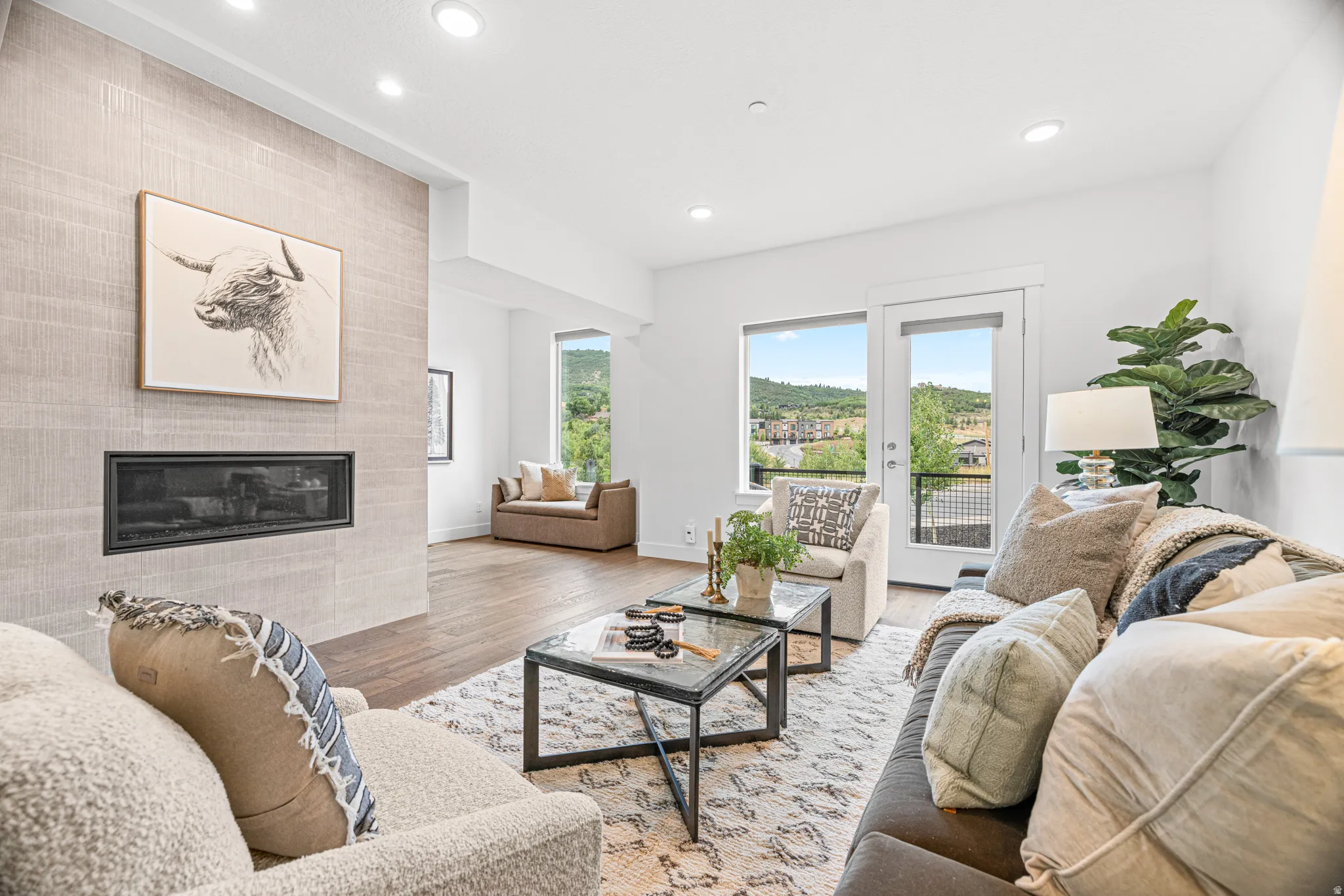 Recessed lighting, wood-finish flooring, and a linear fireplace with a textured surround
