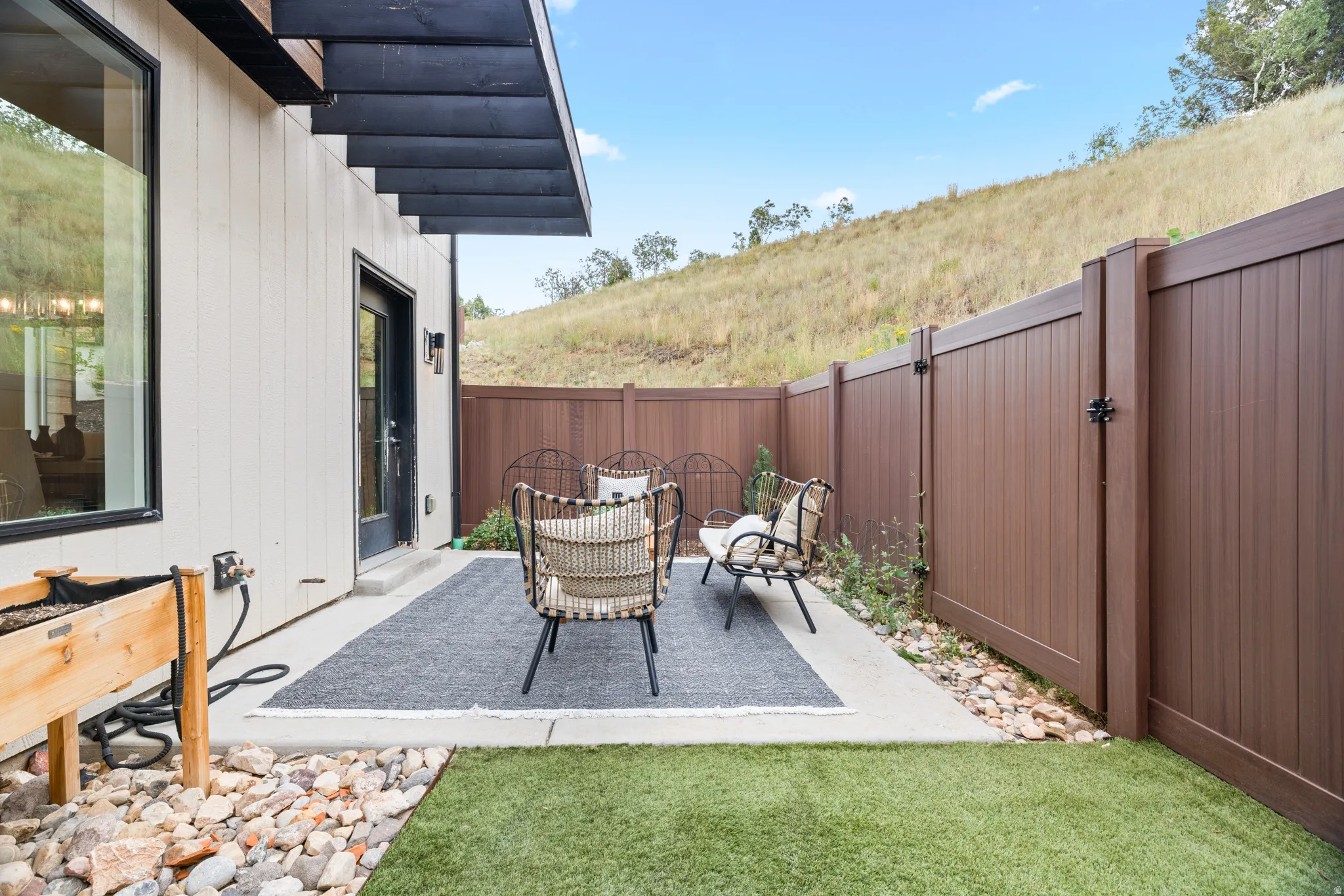 Private patio with concrete surfacing, artificial turf, and a wood-finish privacy fence
