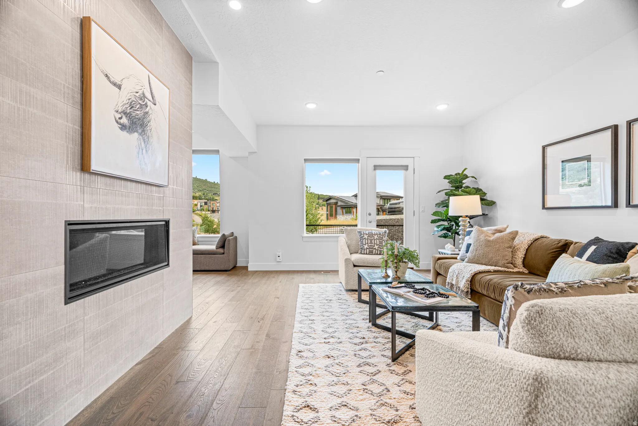 Recessed gas fireplace with a tiled surround, wood-finish flooring, and ample natural light from multiple windows