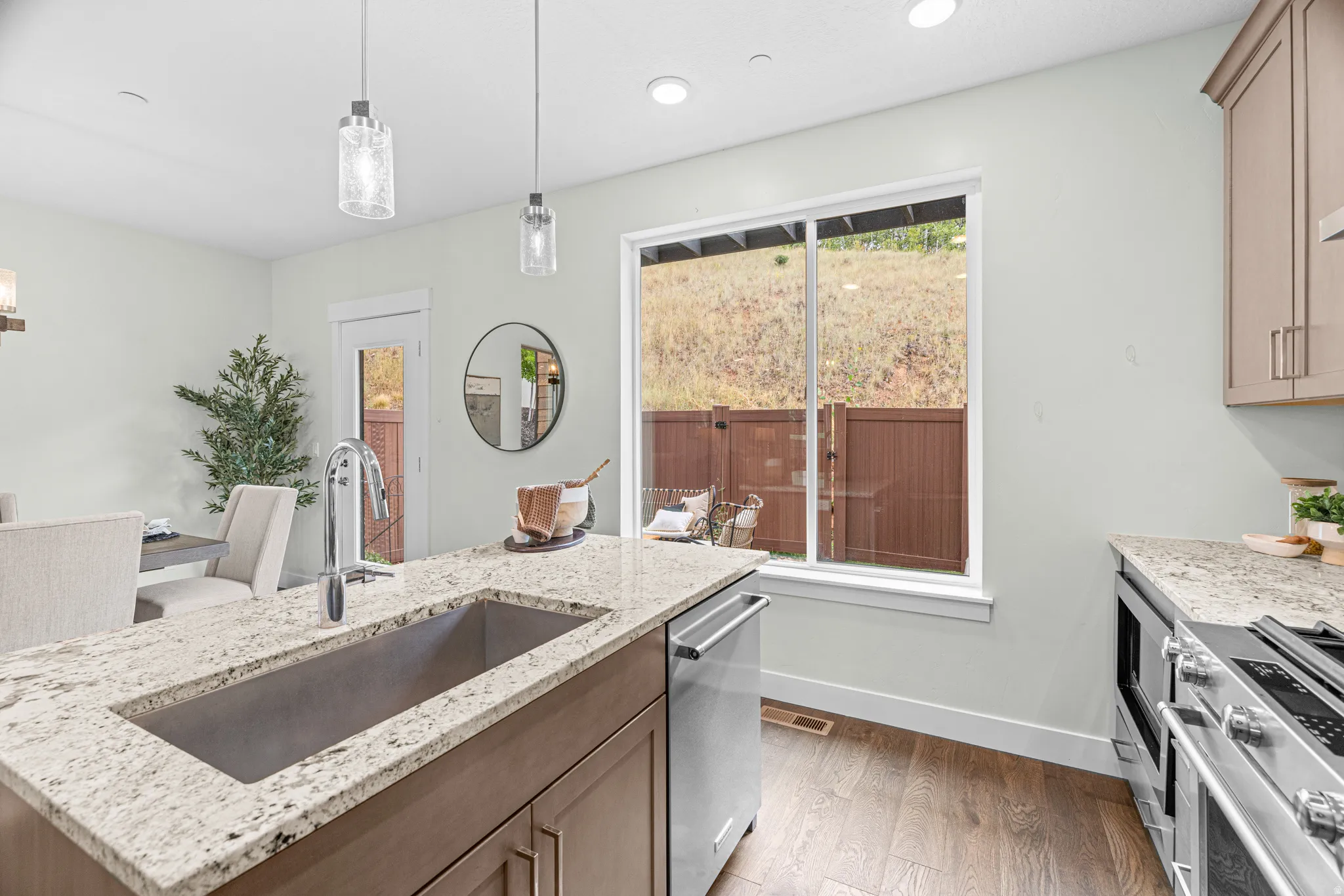 Kitchen featuring a granite-finish island with an undermount sink, stainless steel appliances, and wood-finish flooring