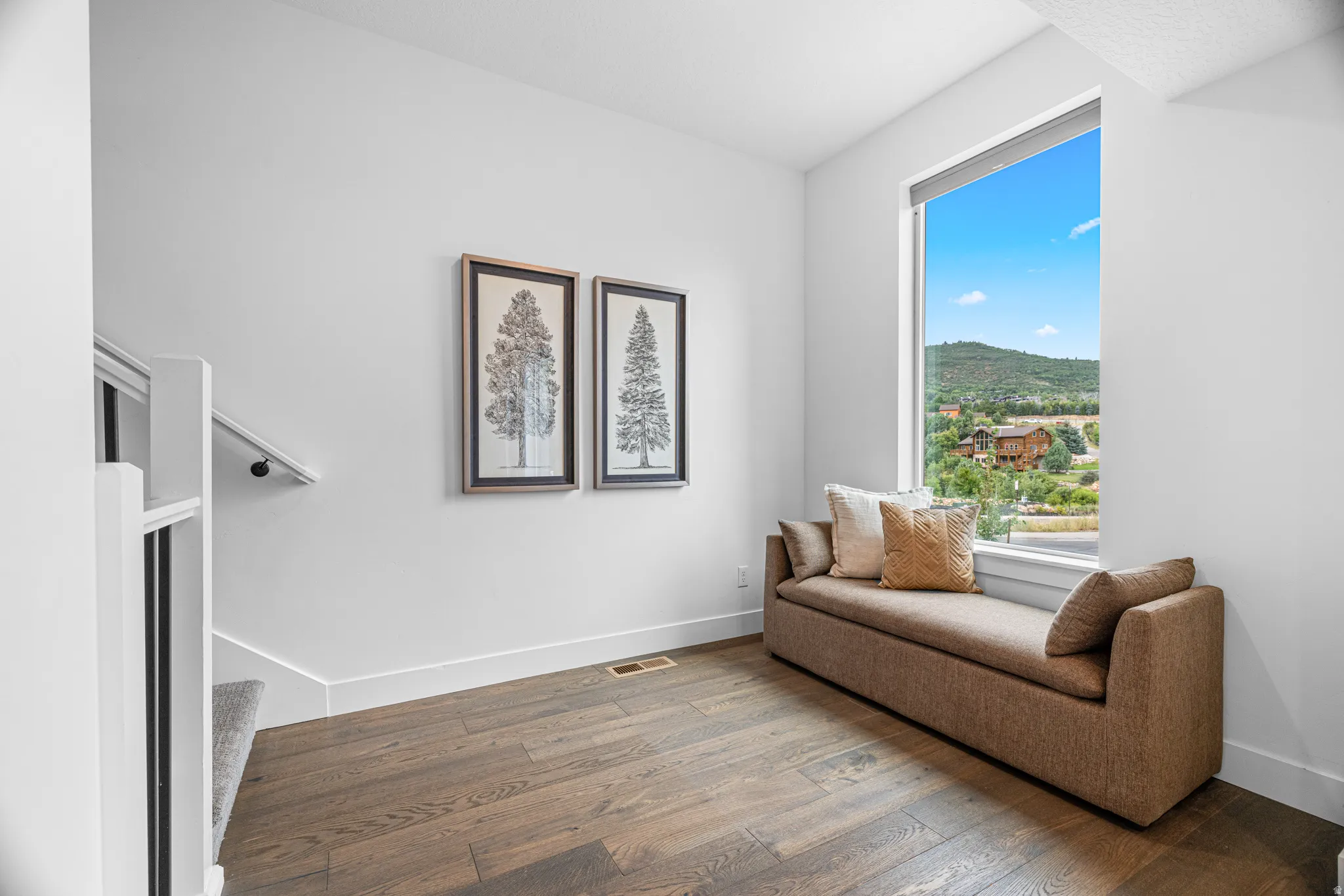 Hardwood flooring, staircase with carpeted treads, white wall finishes, large window, and mountain scenery