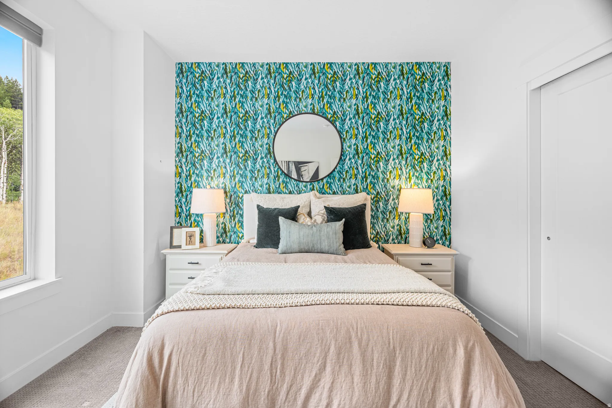 White walls with a feature wall of patterned wallpaper, large window, and carpeted flooring