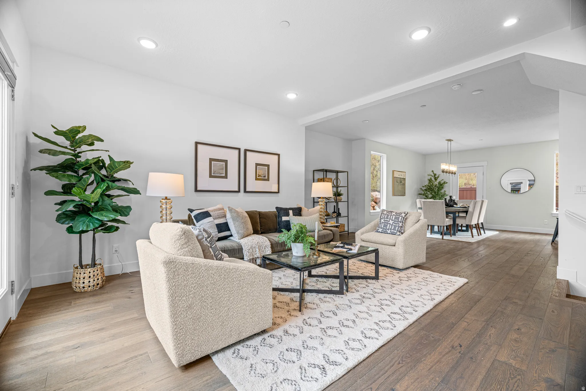 Open-concept living area featuring wood-finish flooring, recessed lighting, and a broad entry to the dining space