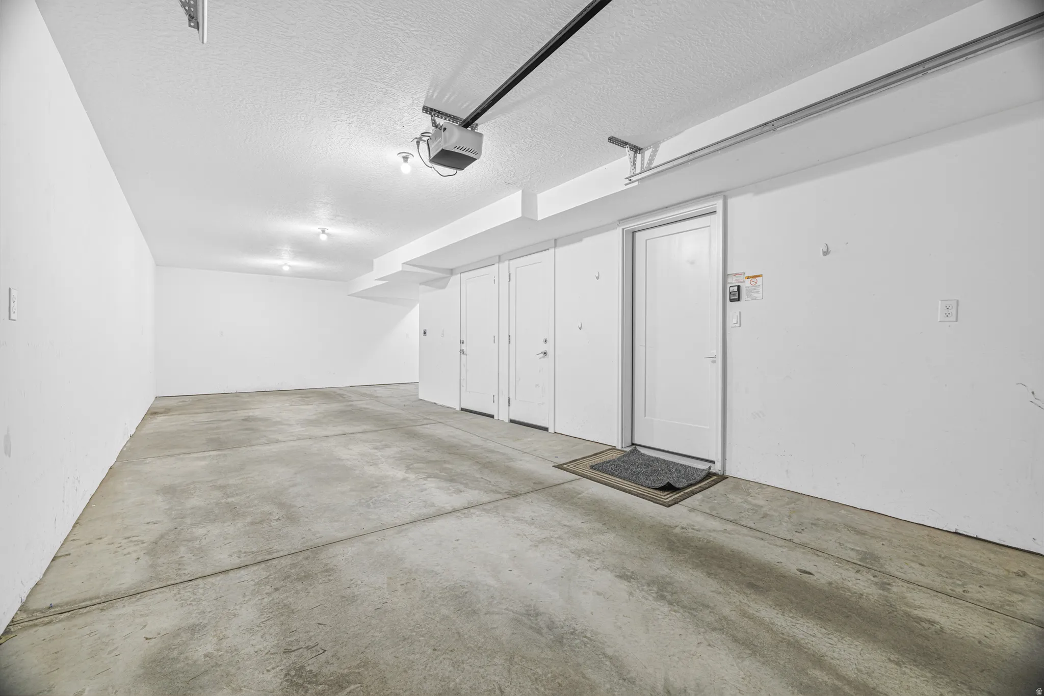 Spacious garage featuring a concrete floor, multiple storage doors, and overhead lighting
