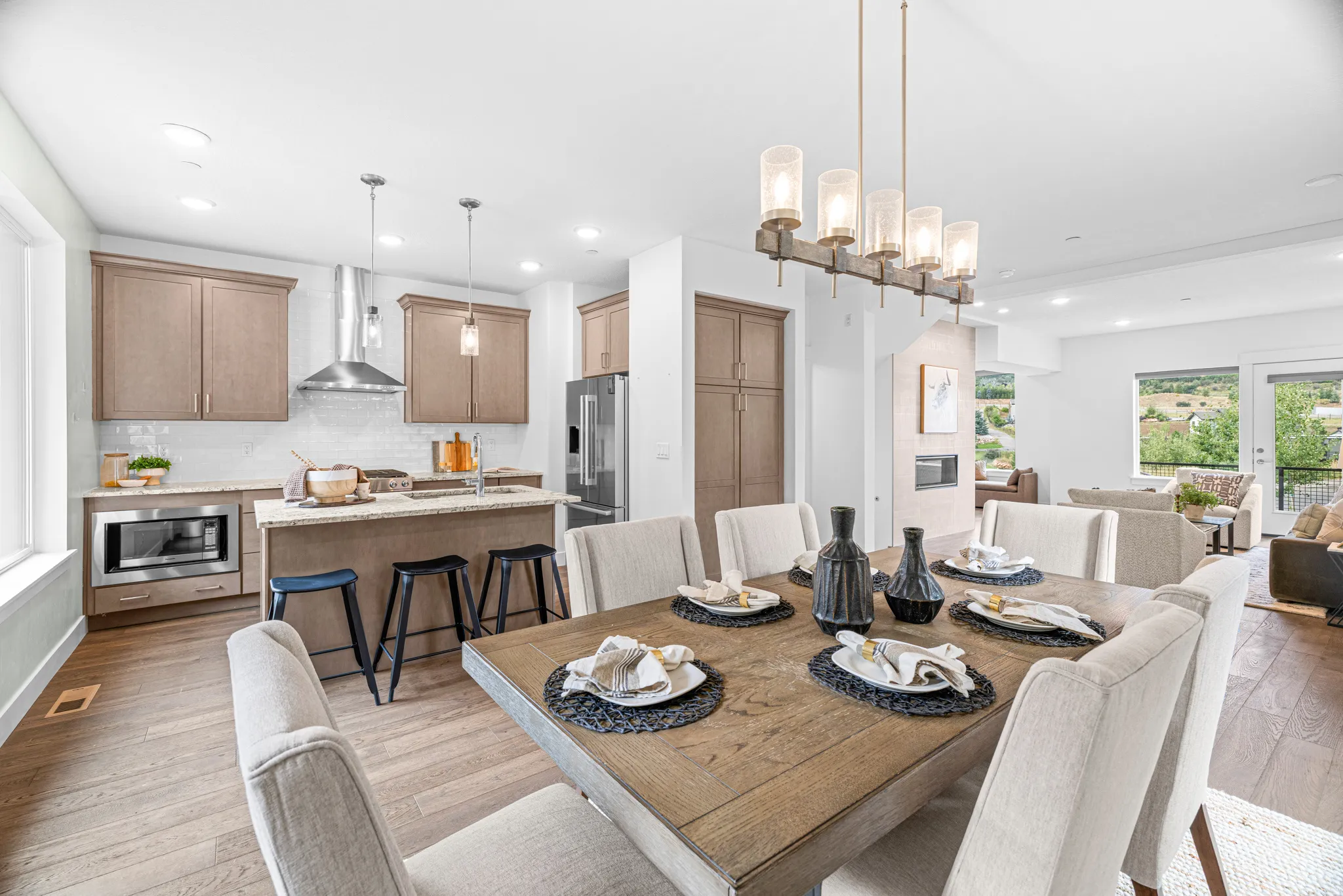 Open-concept living space with wood-finish flooring, a contemporary dining chandelier, and a kitchen featuring stainless steel appliances, a center island, and neutral cabinetry