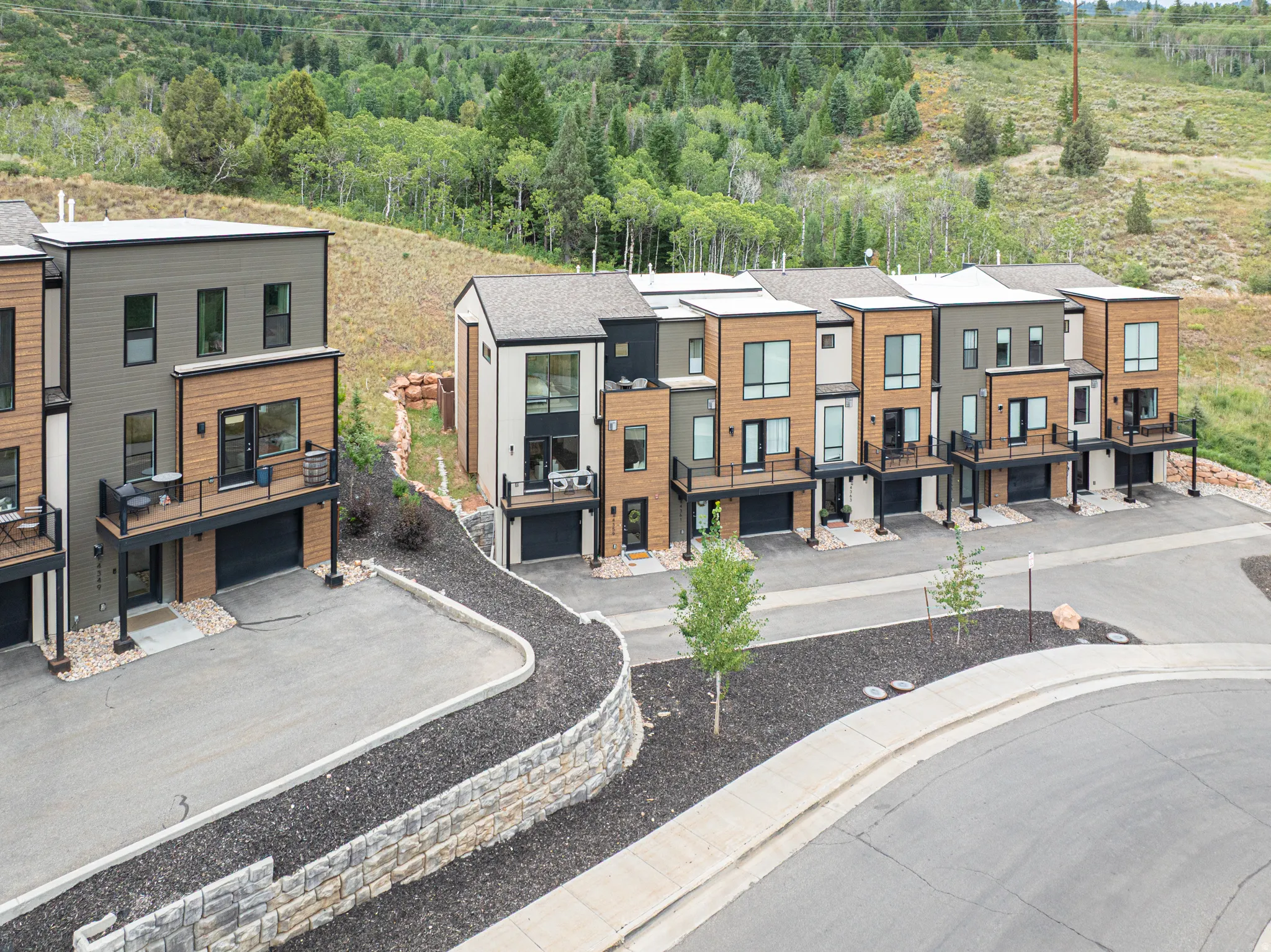Modern townhome exteriors featuring wood-look siding, attached garages, and private balconies with black railings