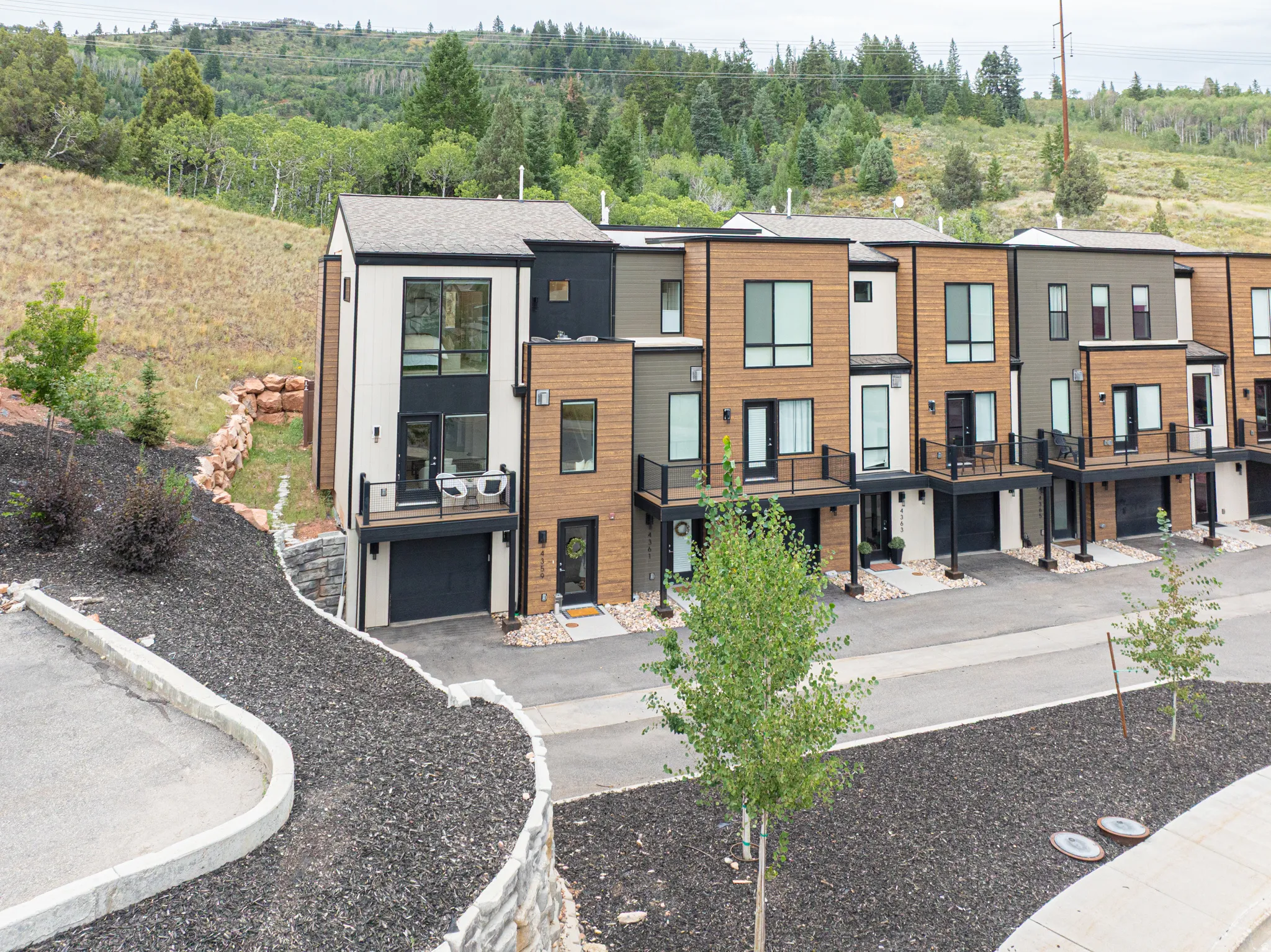 Modern townhome architecture featuring vertical and horizontal siding, multiple balconies with dark railings, and attached garage