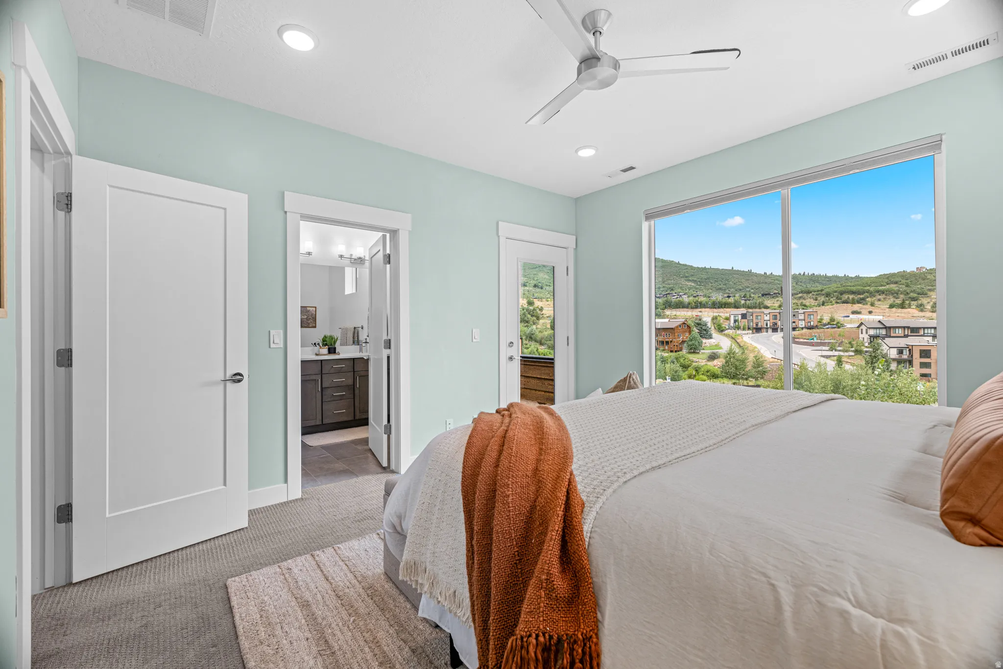Expansive windows, glass panel door, modern ceiling fan, recessed lighting, and carpeted flooring