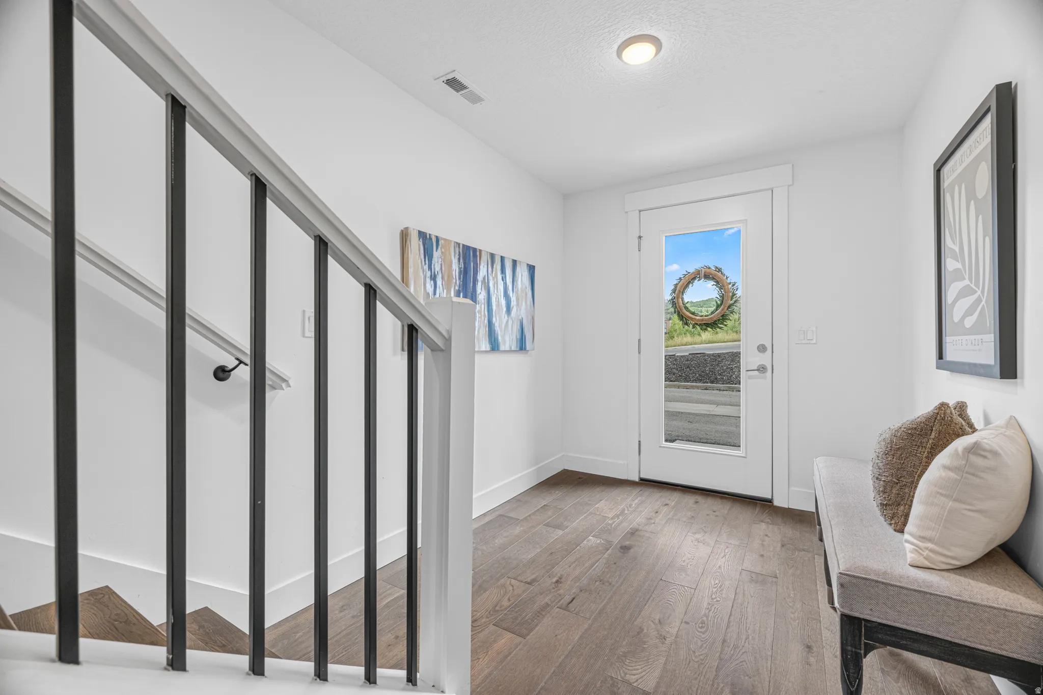 Wood-finish flooring throughout, with a contemporary white front door featuring a full-light panel
