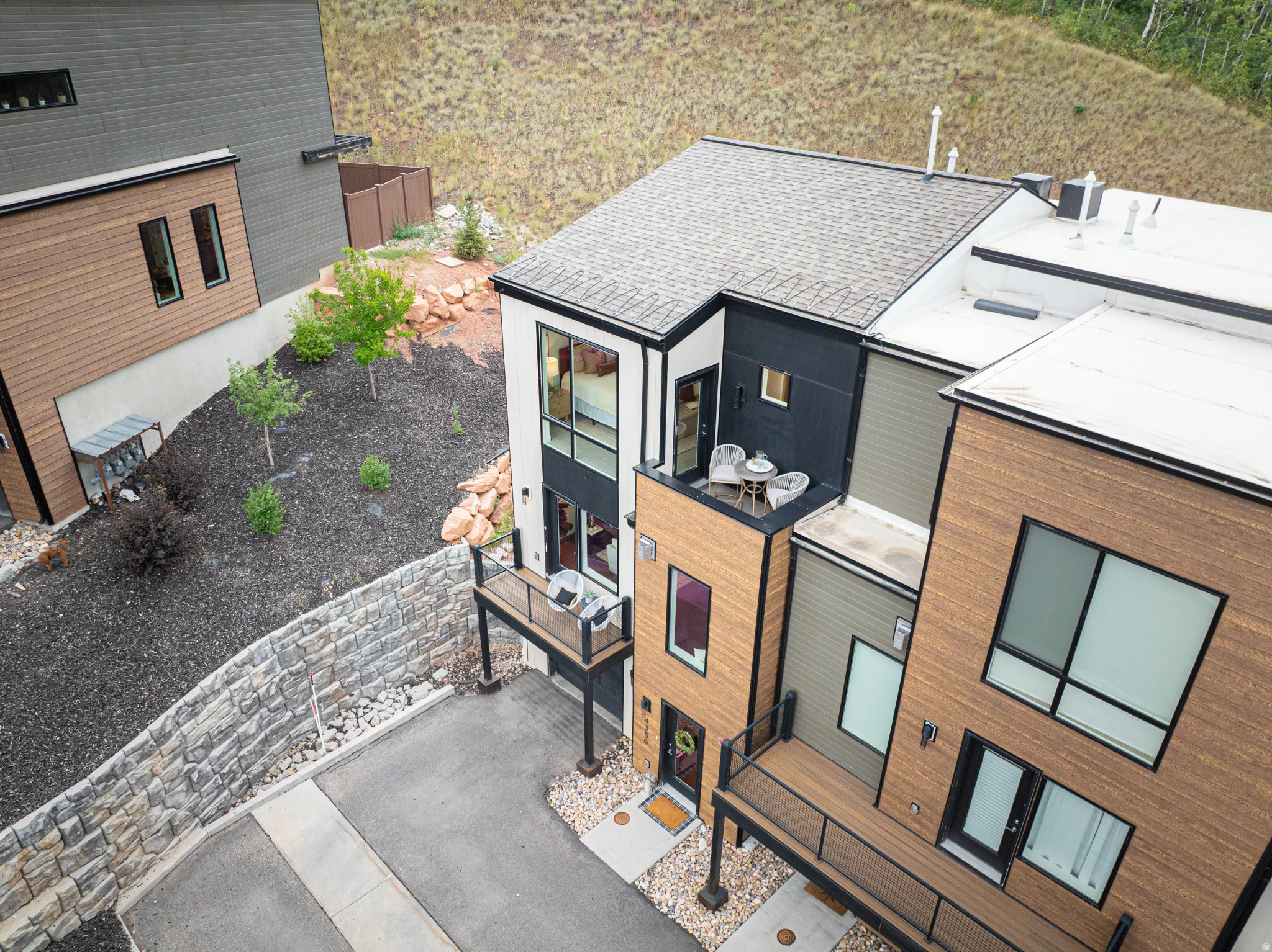 Contemporary multi-level exterior with mixed material siding, multiple private balconies, and a stone retaining wall