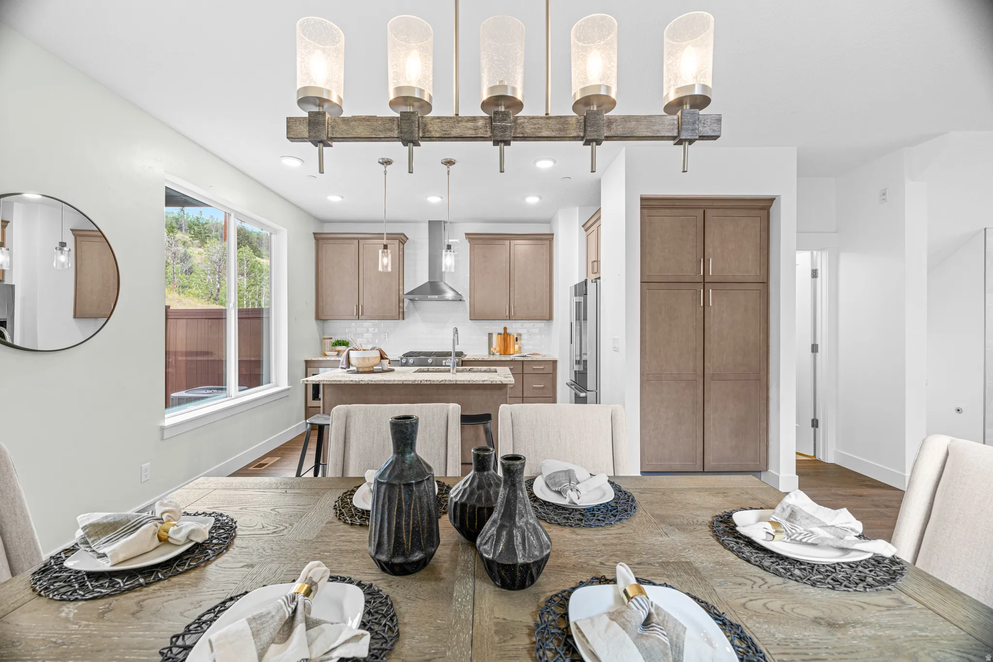 Open-concept living space with a contemporary linear chandelier and wood-finish flooring