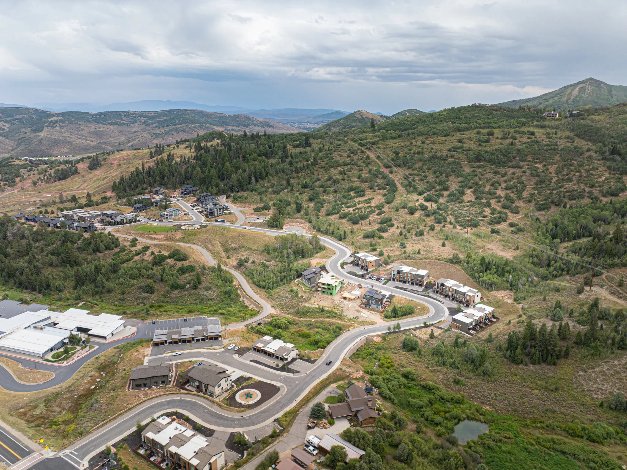 Mountainous terrain with lush green foliage, winding roads, and residential structures