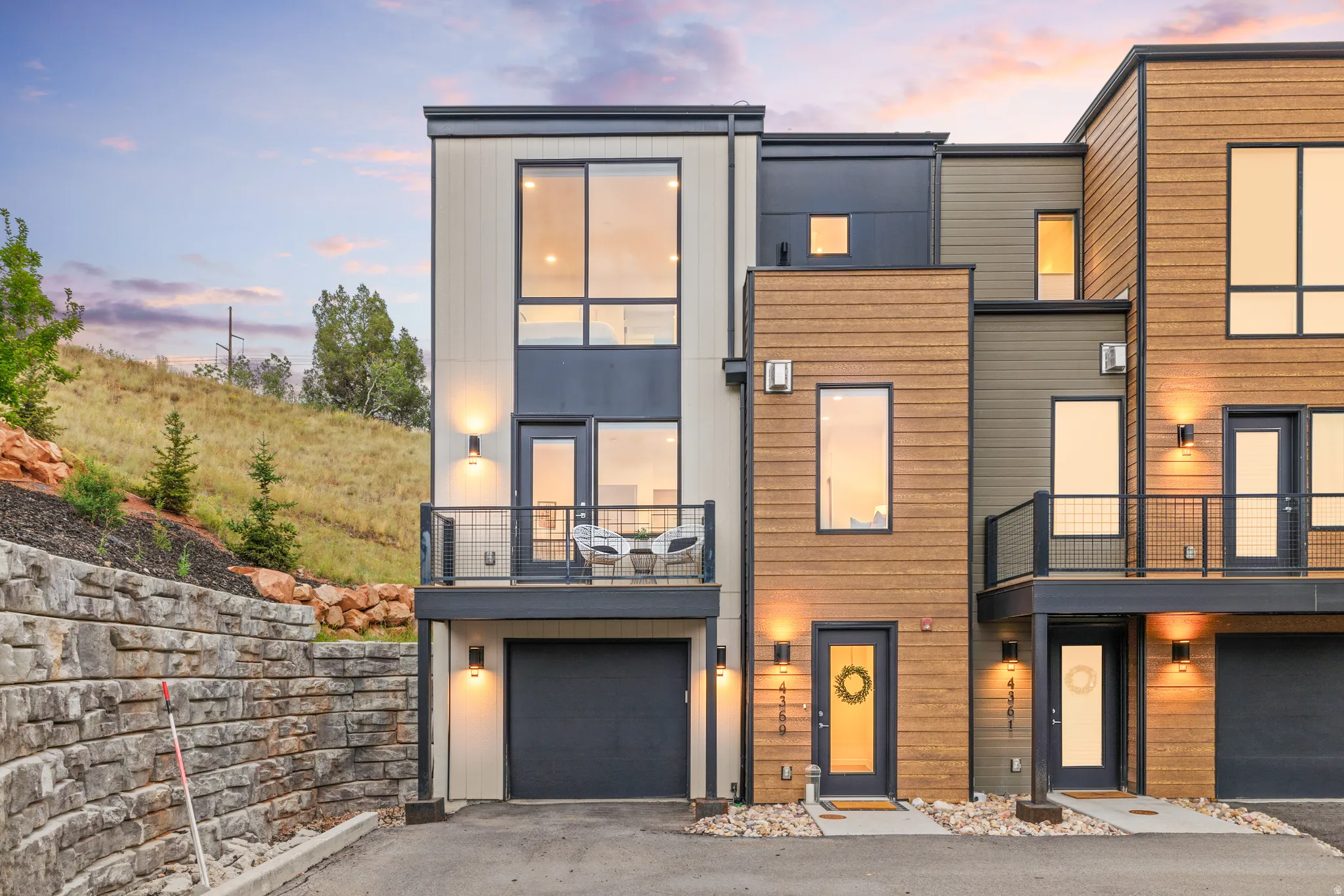 Modern townhome with multi-level architecture, wood-finish siding, and integrated exterior lighting