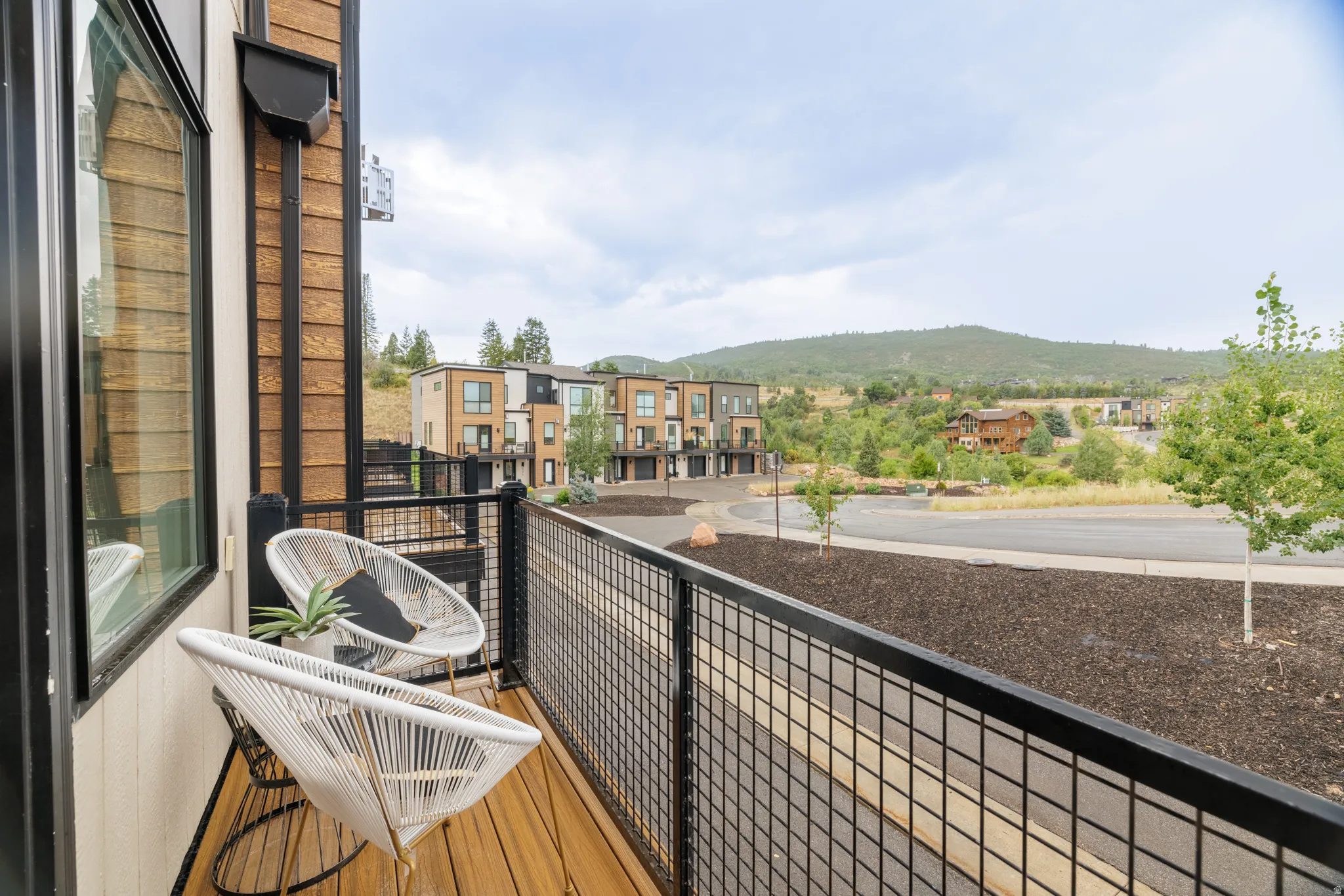 Balcony featuring wood-finish decking, black metal railing, and exterior wood siding