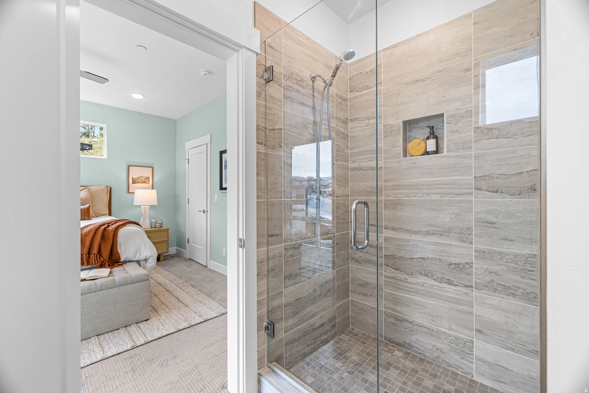Walk-in shower with clear glass enclosure and light-toned tile surround