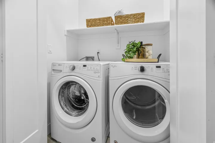 Laundry area featuring front-loading machines and an overhead storage shelf