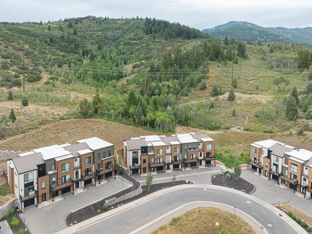 Contemporary townhomes featuring multi-tone facades with wood-look siding, dark gray accents, and light-colored panels