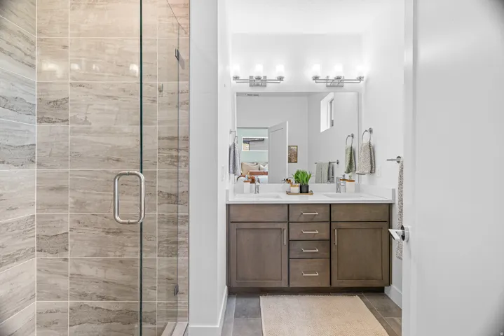 Walk-in shower with full-height tile surround, clear glass enclosure, and chrome hardware