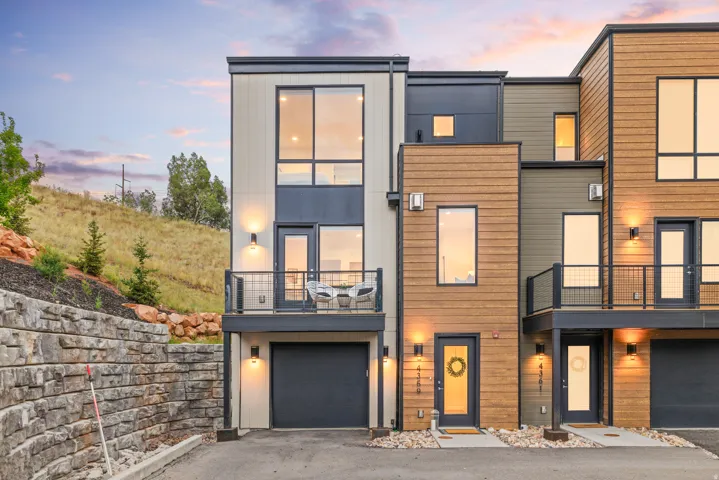 Modern multi-story facade featuring mixed siding, a private balcony, and an integrated garage