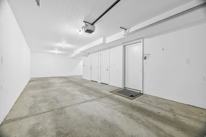 Spacious garage featuring a concrete floor, multiple storage doors, and overhead lighting