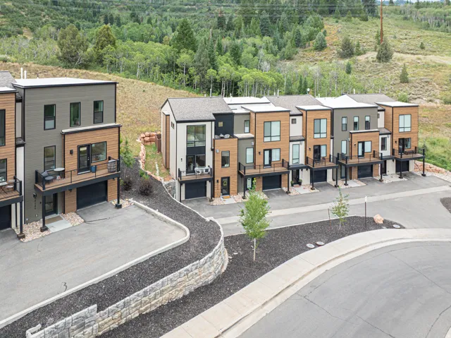 Modern townhome exteriors featuring wood-look siding, attached garages, and private balconies with black railings