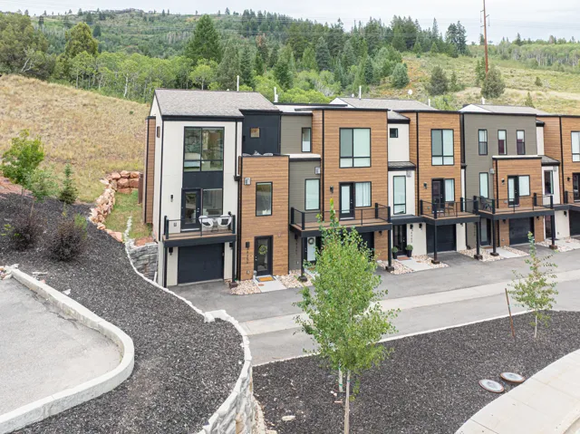 Modern townhome architecture featuring vertical and horizontal siding, multiple balconies with dark railings, and attached garage