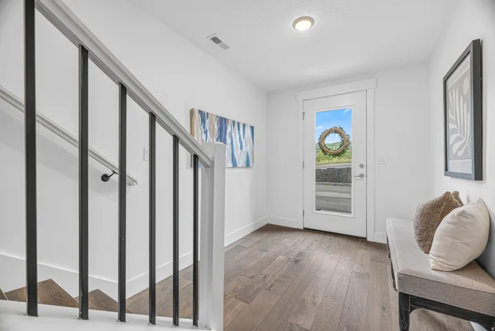 Wood-finish flooring throughout, with a contemporary white front door featuring a full-light panel