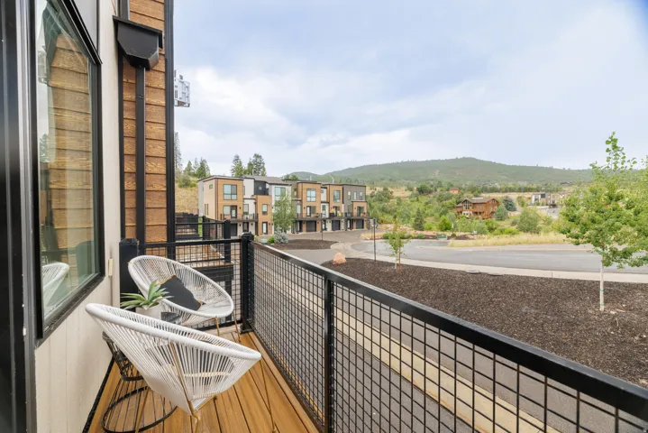 Balcony featuring wood-finish decking, black metal railing, and exterior wood siding