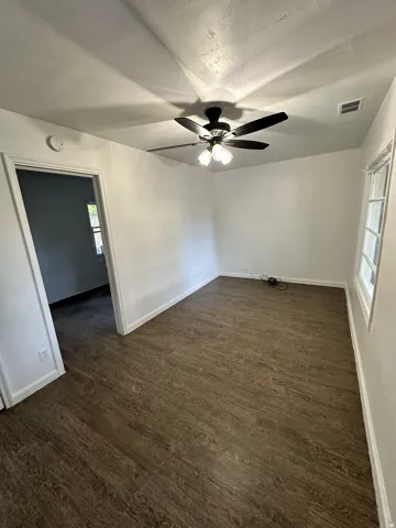 Wood-finish flooring, ceiling fan with integrated lighting, recessed window, and white trim