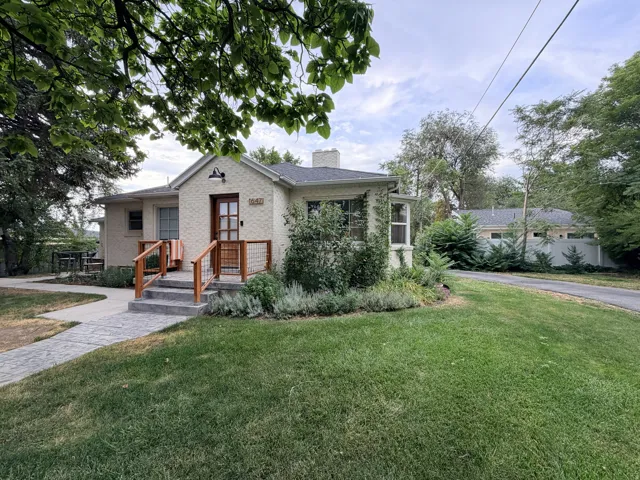 Exterior featuring a wood entry door, front porch with wood and cable railing, concrete steps, and a landscaped garden