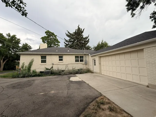 Attached garage with a panel-style door, concrete driveway, and brick exterior