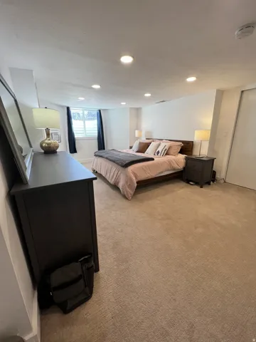 Recessed lighting, light-colored walls, and neutral carpeting