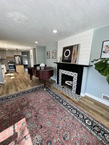 Recessed lighting, wood-finish flooring, and a fireplace with a decorative tile surround and black mantel
