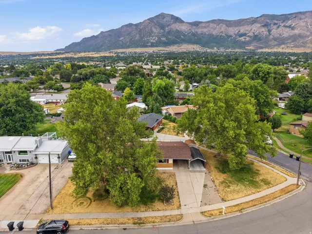 Mountain backdrop with extensive residential area, corner lot property, mature trees, and a concrete driveway with an attached carport