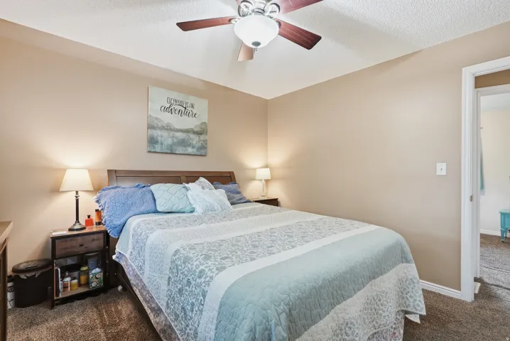 Recessed ceiling fan with wood-finish blades, soft brown wall color, and textured carpet flooring