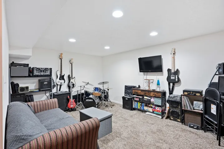 Recessed lighting illuminates this versatile space featuring neutral carpeting and white wall finishes