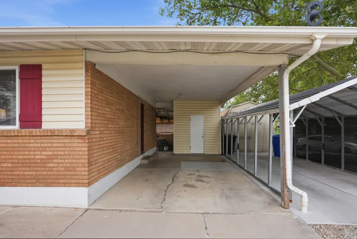 Covered carport with concrete flooring, brick and siding exterior, and a storage shed