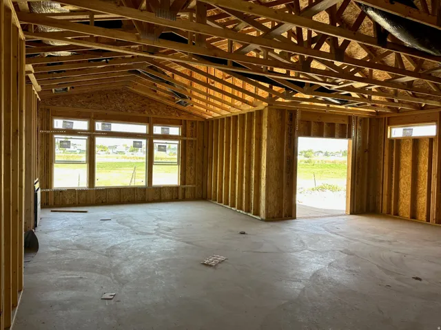 Open-concept framing with vaulted ceilings, multiple windows, and a concrete slab foundation